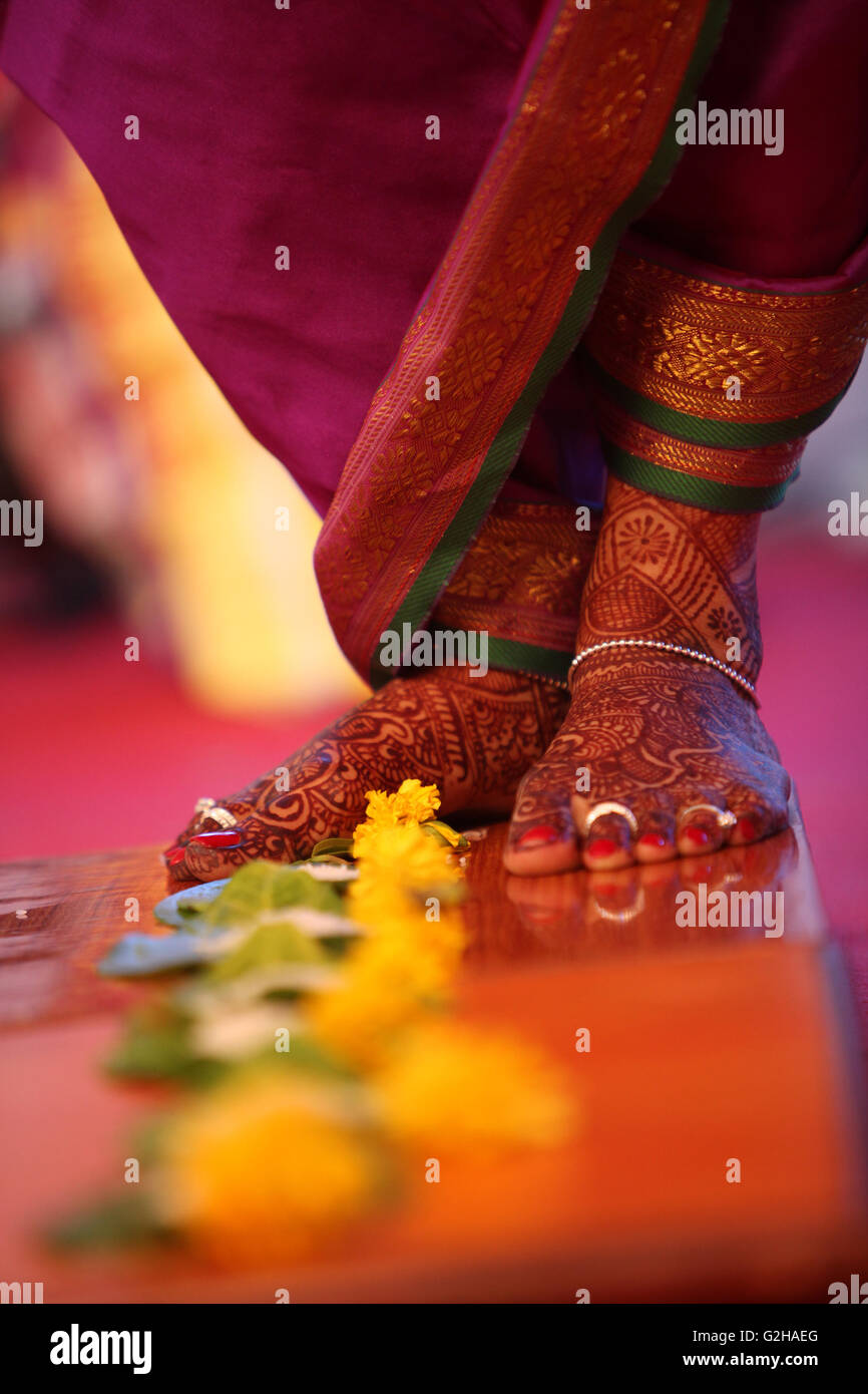 Les pieds de la mariée au cours d'un rituel de mariage traditionnel indien de l'progression plus de fleurs. Banque D'Images