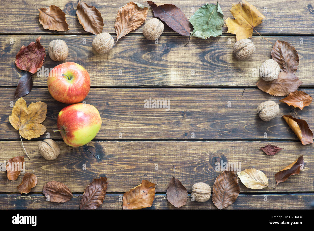 Les feuilles d'automne, les pommes et les noix sur fond de bois Banque D'Images