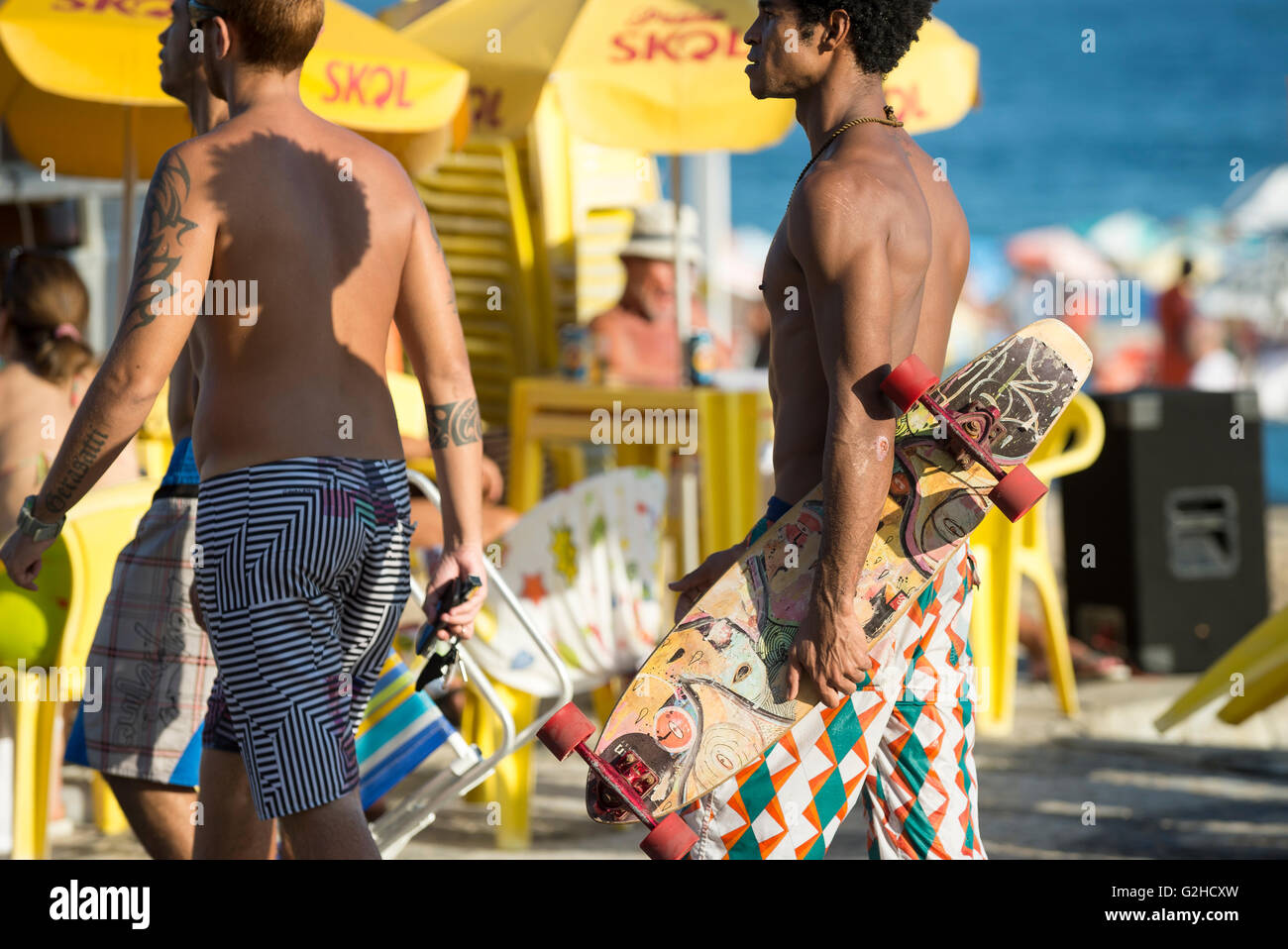 RIO DE JANEIRO - le 6 mars 2016 : Carioca brésiliens marcher devant un kiosque jaune sur le front promenade à la plage d'Ipanema. Banque D'Images
