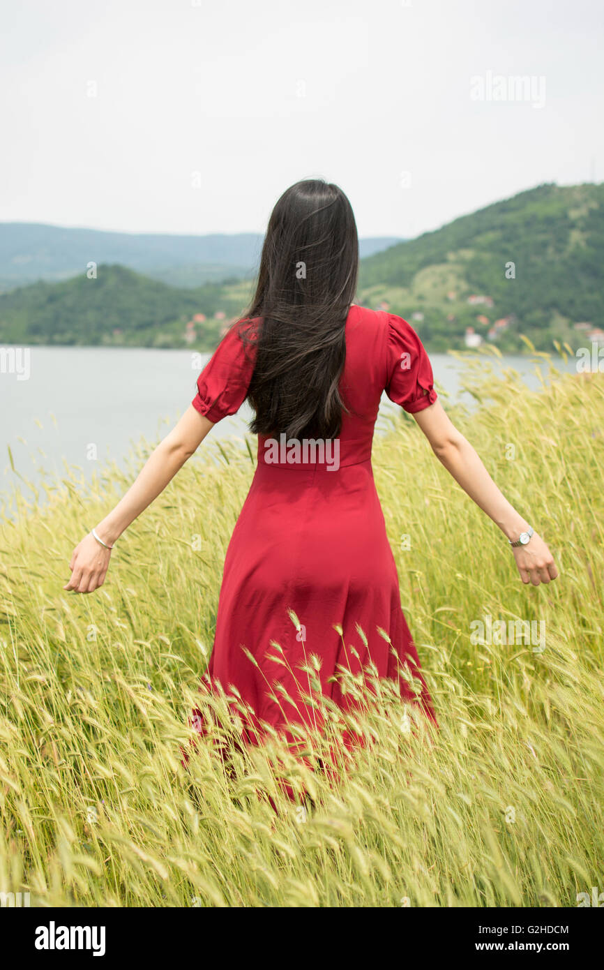 Fille à la mode dans un champ de blé wearing red dress Banque D'Images