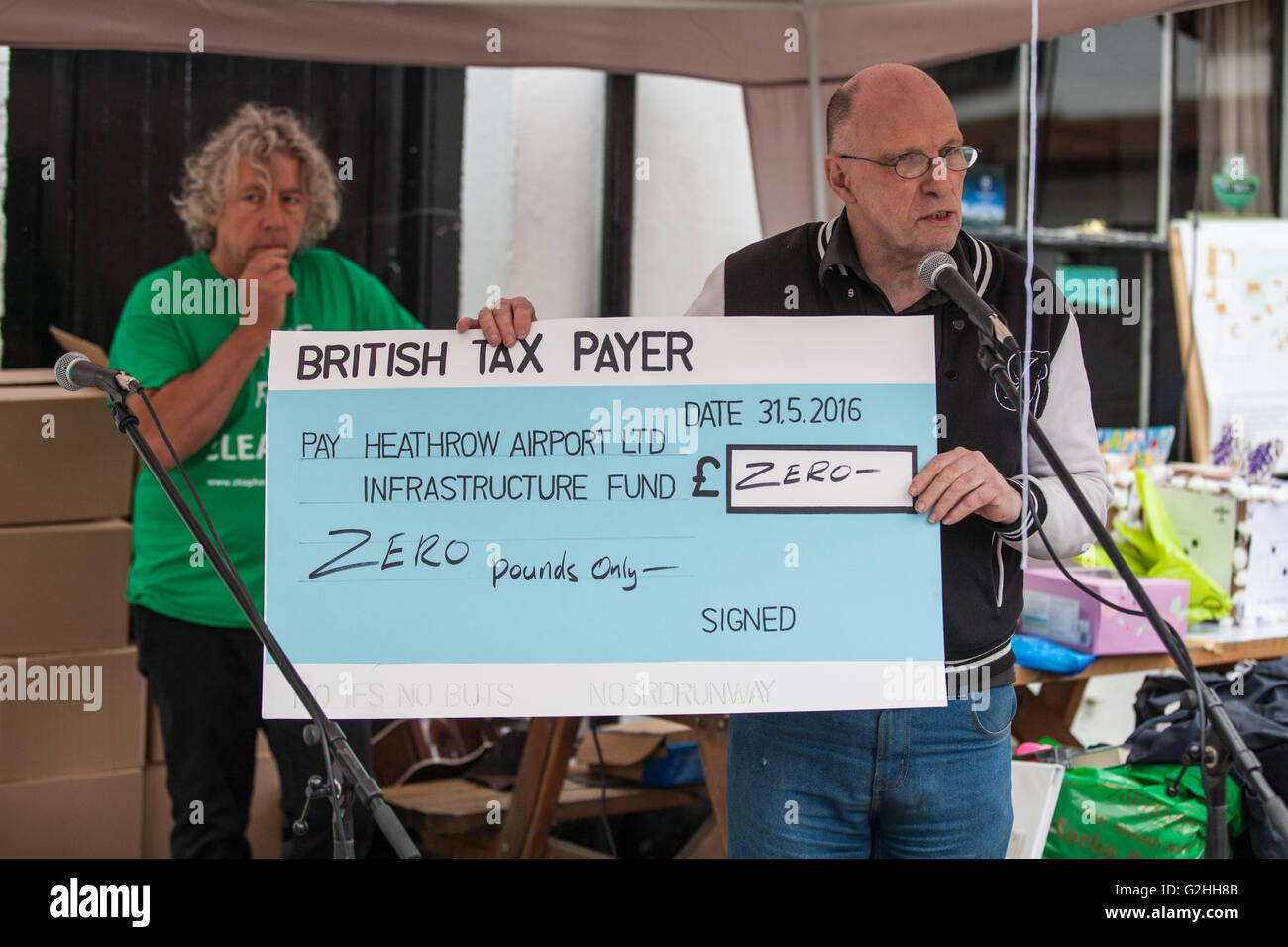 Harmondsworth, UK. 30 mai, 2016. John Stewart de HACAN (Heathrow Association pour la lutte contre le bruit des avions) est titulaire d'un 70e anniversaire de l'aéroport de Heathrow, un chèque géant pour l'aéroport Heathrow Infrastructure Fund Ltd, comme il traite de militants contre l'expansion d'Heathrow à Harmondsworth village. Une grande partie de Harmondsworth serait aplati doit des plans pour une 3e piste soit approuvé. Credit : Mark Kerrison/Alamy Live News Banque D'Images