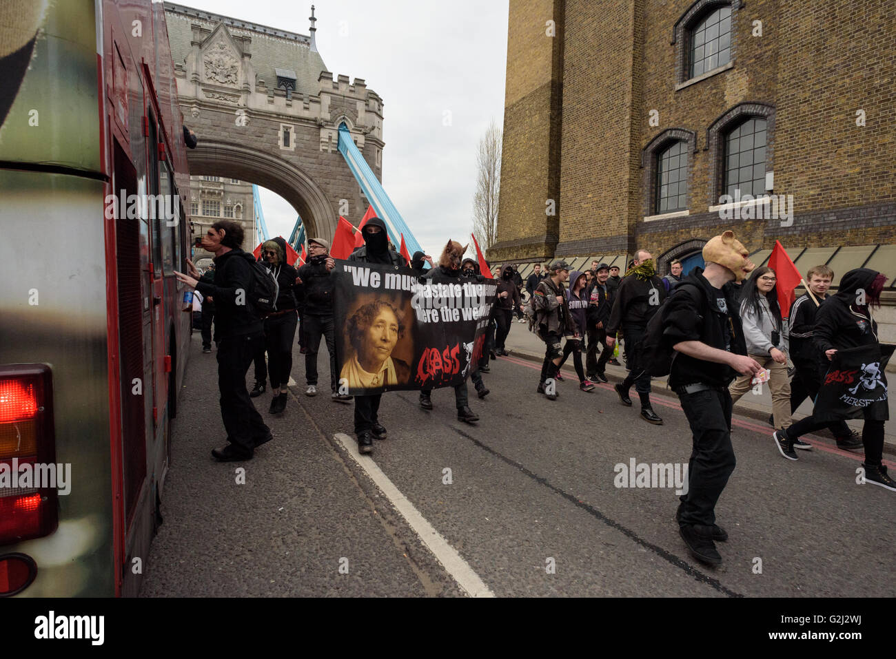 Groupe anarchiste du Premier Mai avec faces cachées, des slogans et des drapeaux rouges marchant sur le Tower Bridge 1er mai 2016 Banque D'Images