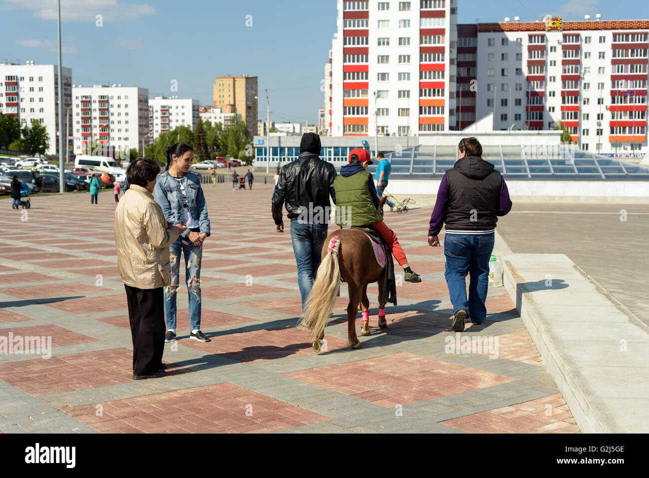 Les jeunes enfants et la famille profitez des promenades en poney dans le soleil à Oufa, République de Bachkirie, Fédération de Russie en 2016 Banque D'Images