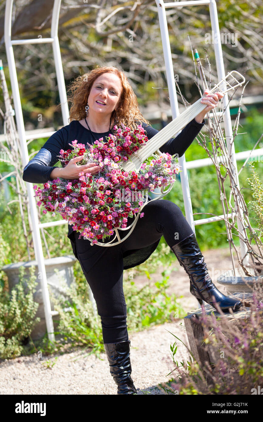 Femme avec un cache-pot en forme de guitare dans son jardin Banque D'Images