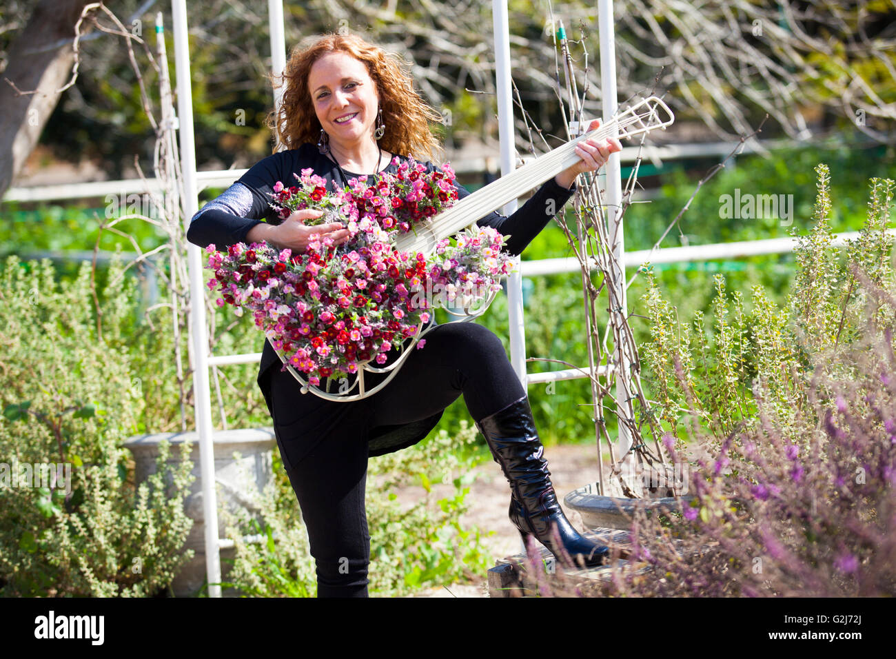 Femme avec un cache-pot en forme de guitare dans son jardin Banque D'Images