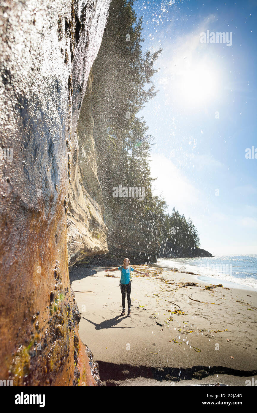 Une jeune femme l'article ci-dessous en cascade le long de la plage mystique Juan de Fuca Trail. L'île de Vancouver, BC, Canada. Banque D'Images