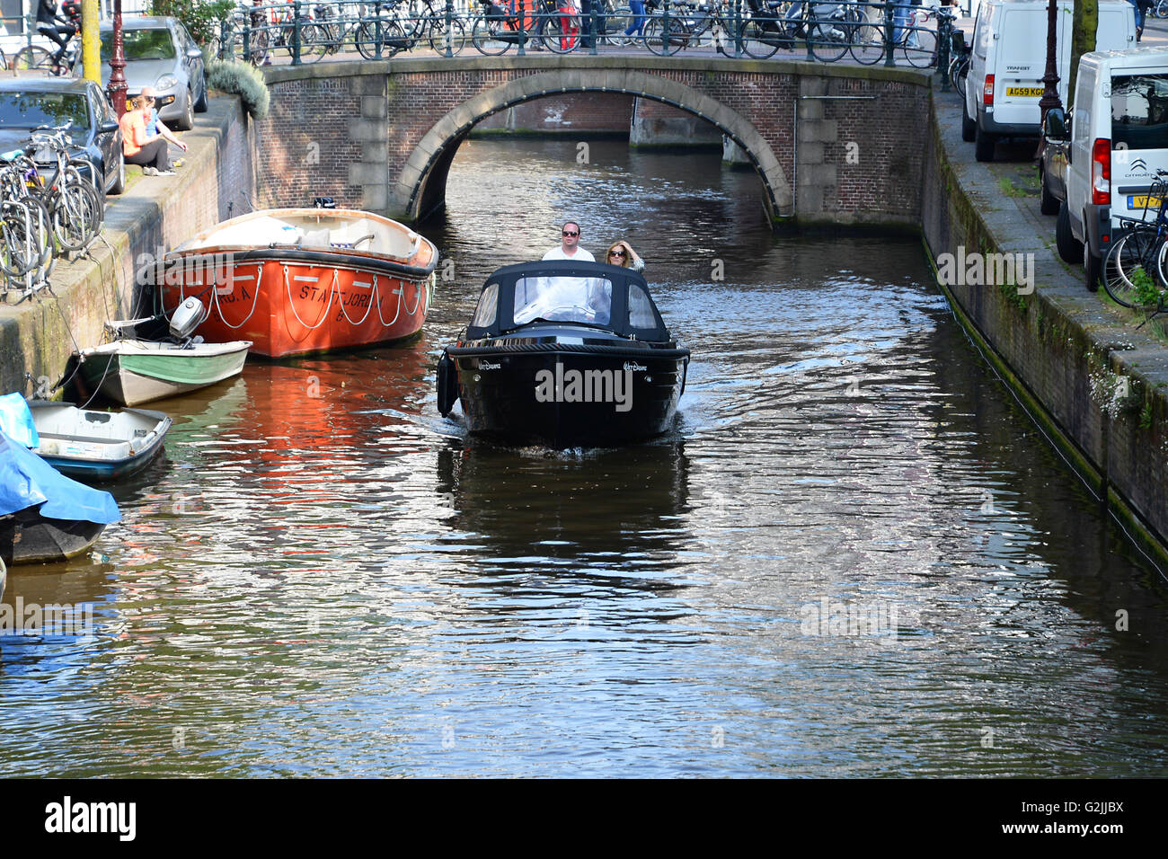 Couple naviguer voile sur canal sous le pont dans le centre-ville d'Amsterdam. Banque D'Images