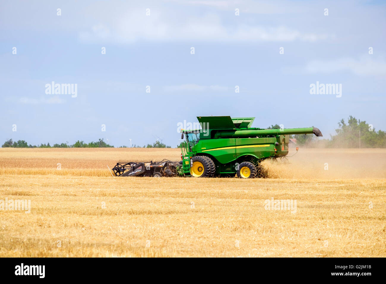 Une moissonneuse-batteuse John Deere récoltes de blé dans l'Oklahoma, USA. Banque D'Images