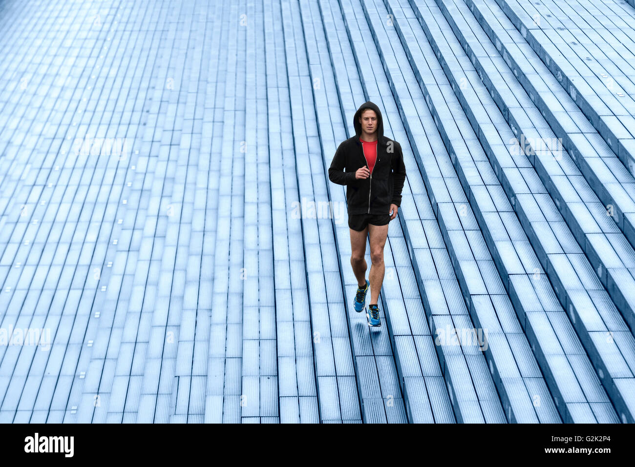 Jogger urbain avec capuche noire. Le jogging piscine Banque D'Images