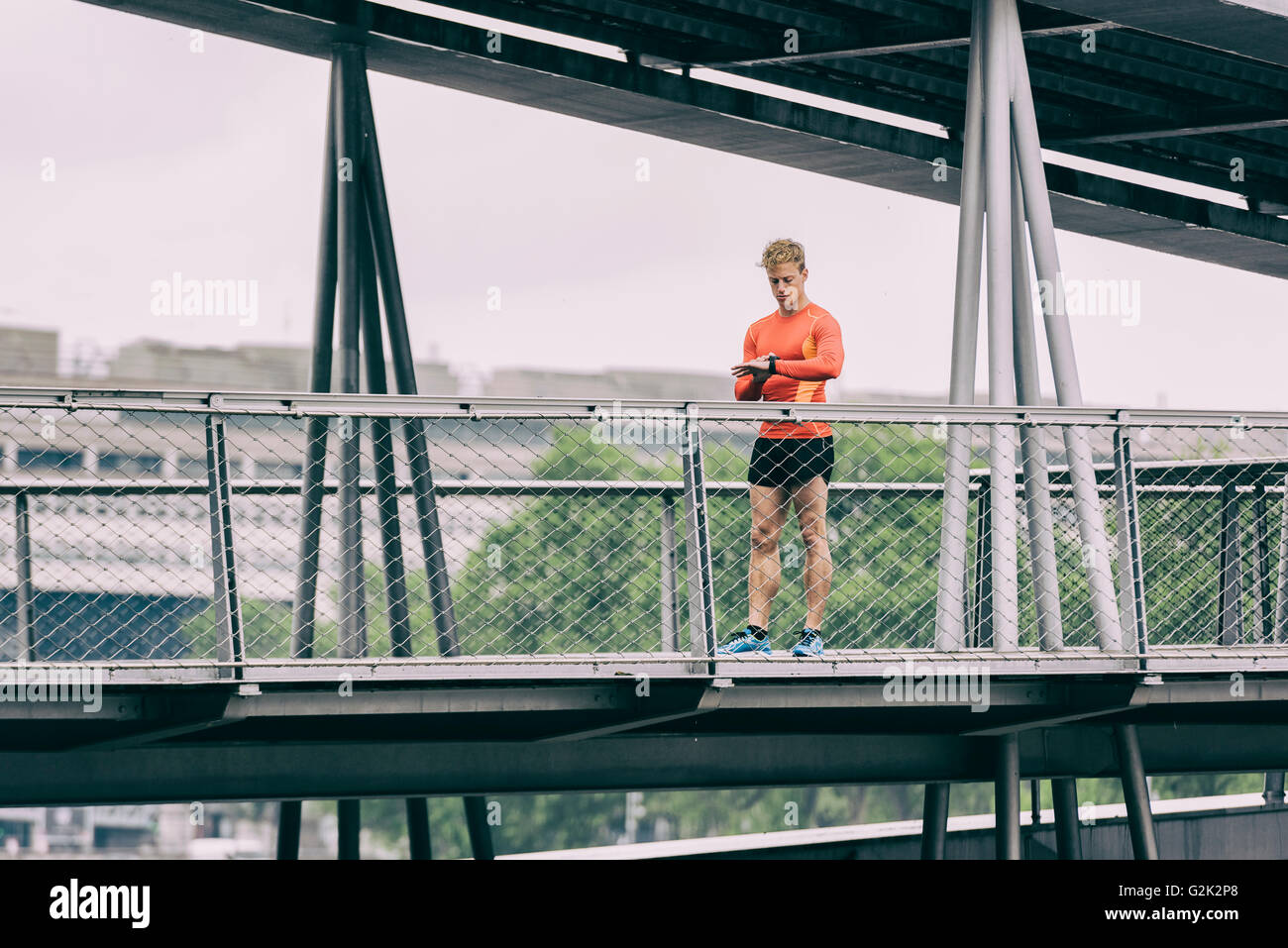 Homme courant à la sportwatch. Homme à l'aide de smart watch jogging runner sur pont métallique Banque D'Images