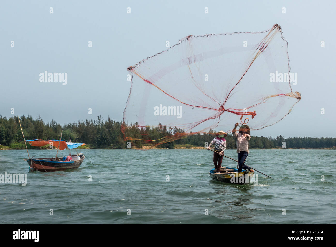 Les pêcheurs locaux de jeter les filets de pêche des bateaux sur le fleuve, Hoi An, Vietnam Banque D'Images