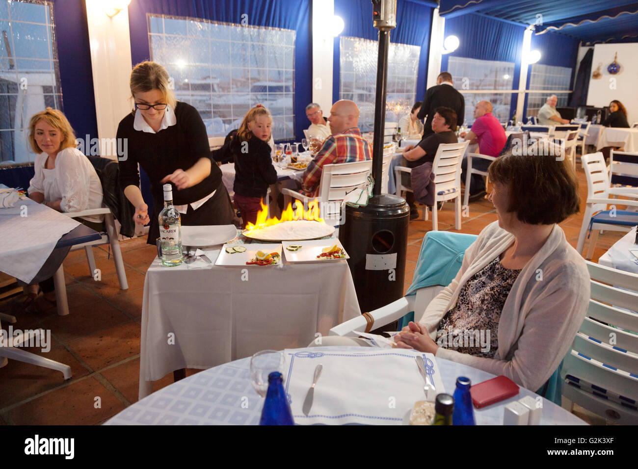 La cuisson du poisson salé cuit flambe et servi dans un restaurant espagnol, Estepona, Malaga, Espagne Europe Banque D'Images