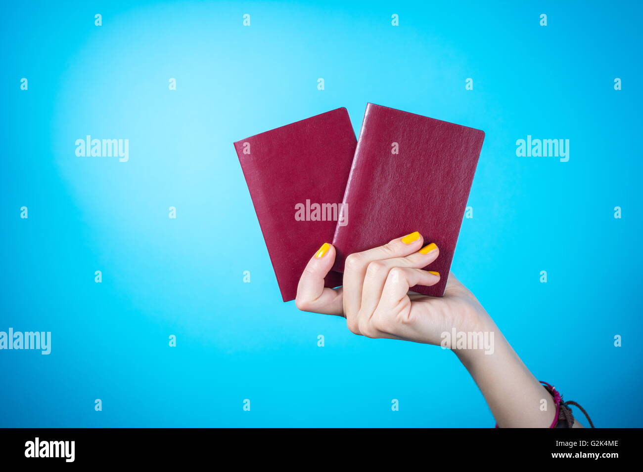 Womans hand holding a deux passeport rouge contre bleu fond Banque D'Images