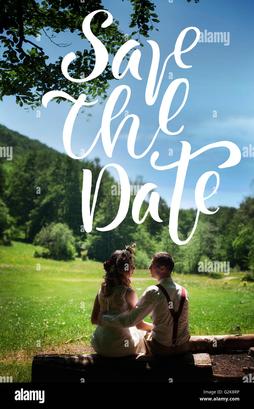 Couple nouvellement marié assis dans un parc et à la recherche d'autres mots à chaque Save the Date Banque D'Images