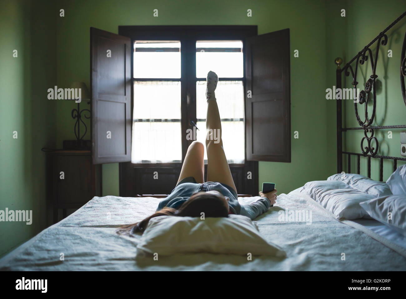 Relaxed woman lying in bed with smartphone Banque D'Images