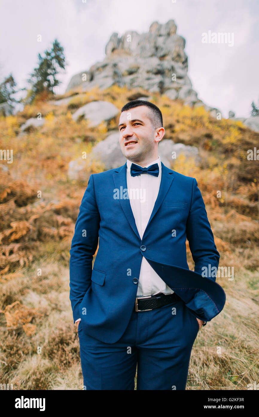 Close-up portrait of handsome groom élégant bleu en costume avec un paysage naturel des Rocheuses en arrière-plan Banque D'Images