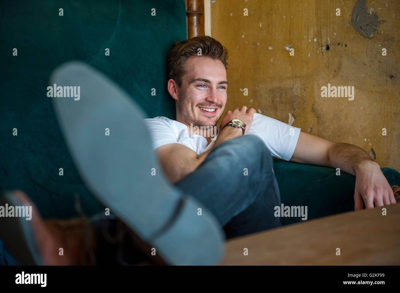 Portrait of happy young man relaxing on couch avec pieds Banque D'Images