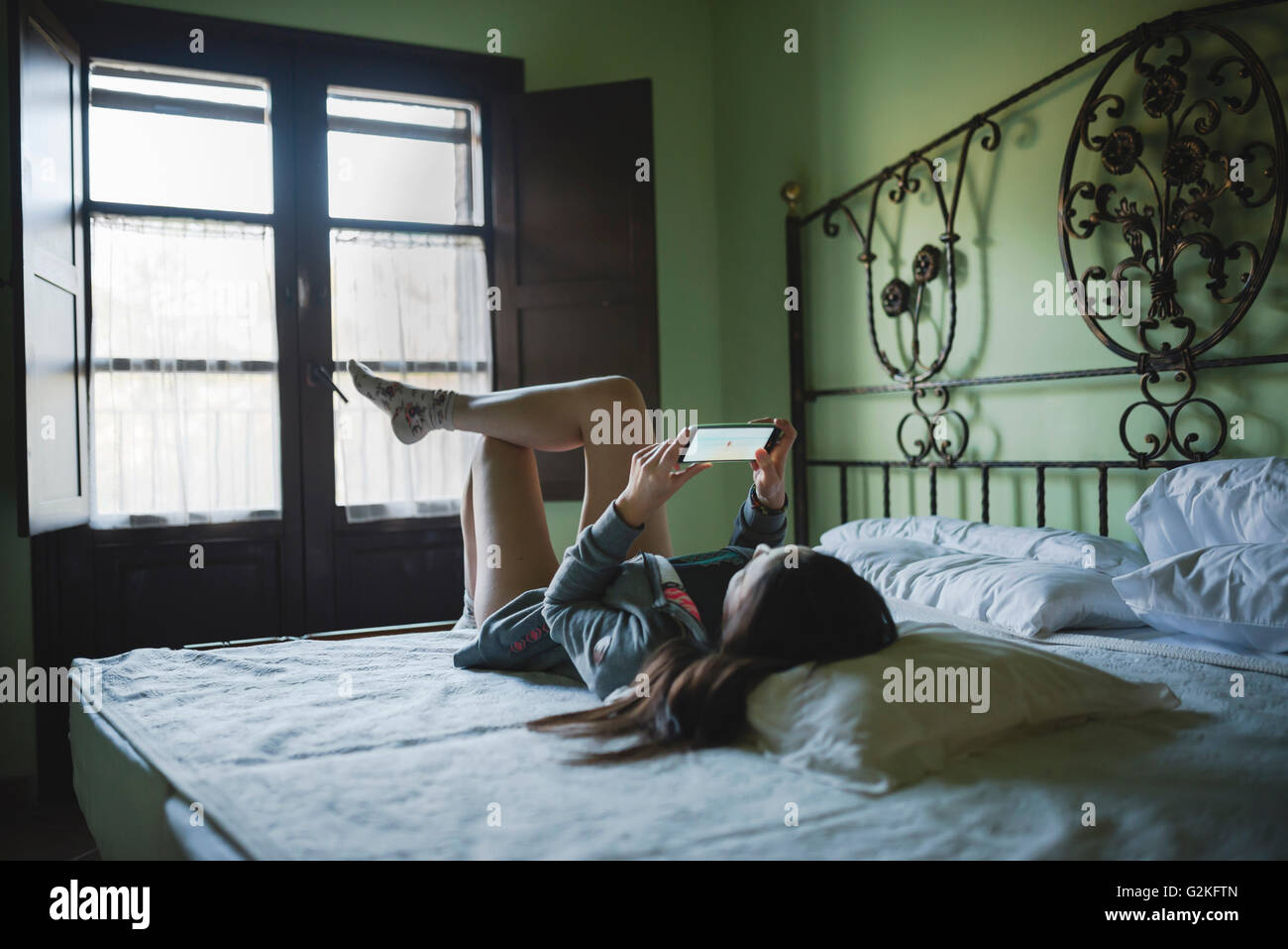 Woman Lying in Bed using smartphone Banque D'Images