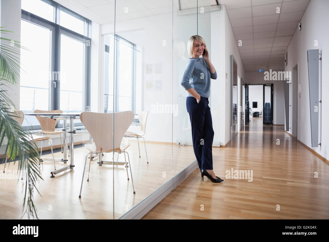 Businesswoman standing in office talking on the phone Banque D'Images
