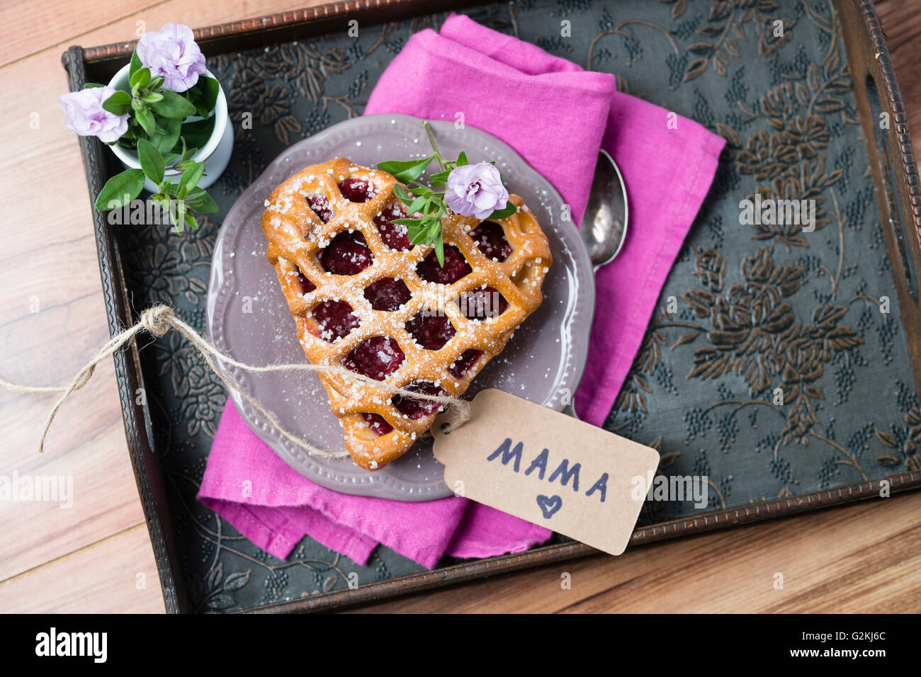 Gâteau cerises en forme de cœur avec l'étiquette-nom et de fleurs sur le bac Banque D'Images