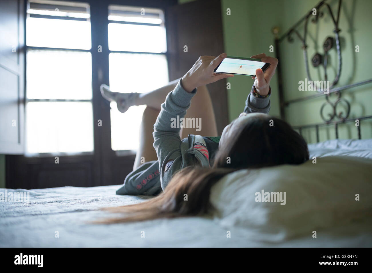 Woman Lying in Bed using smartphone Banque D'Images