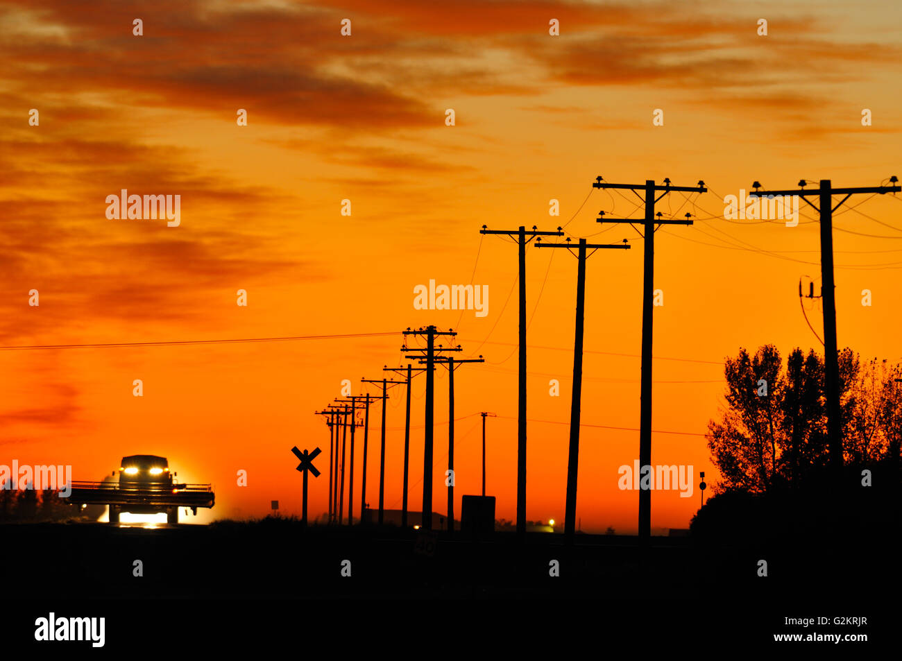 La moissonneuse-batteuse en bas de la route au coucher du soleil Tuxford Saskatchewan Canada Banque D'Images