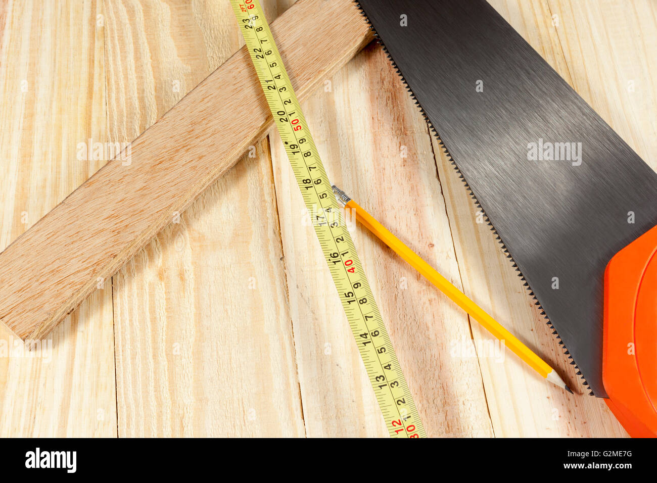 Scie à main portant sur le plancher avec un ruban à mesurer et couper un morceau de bois Banque D'Images