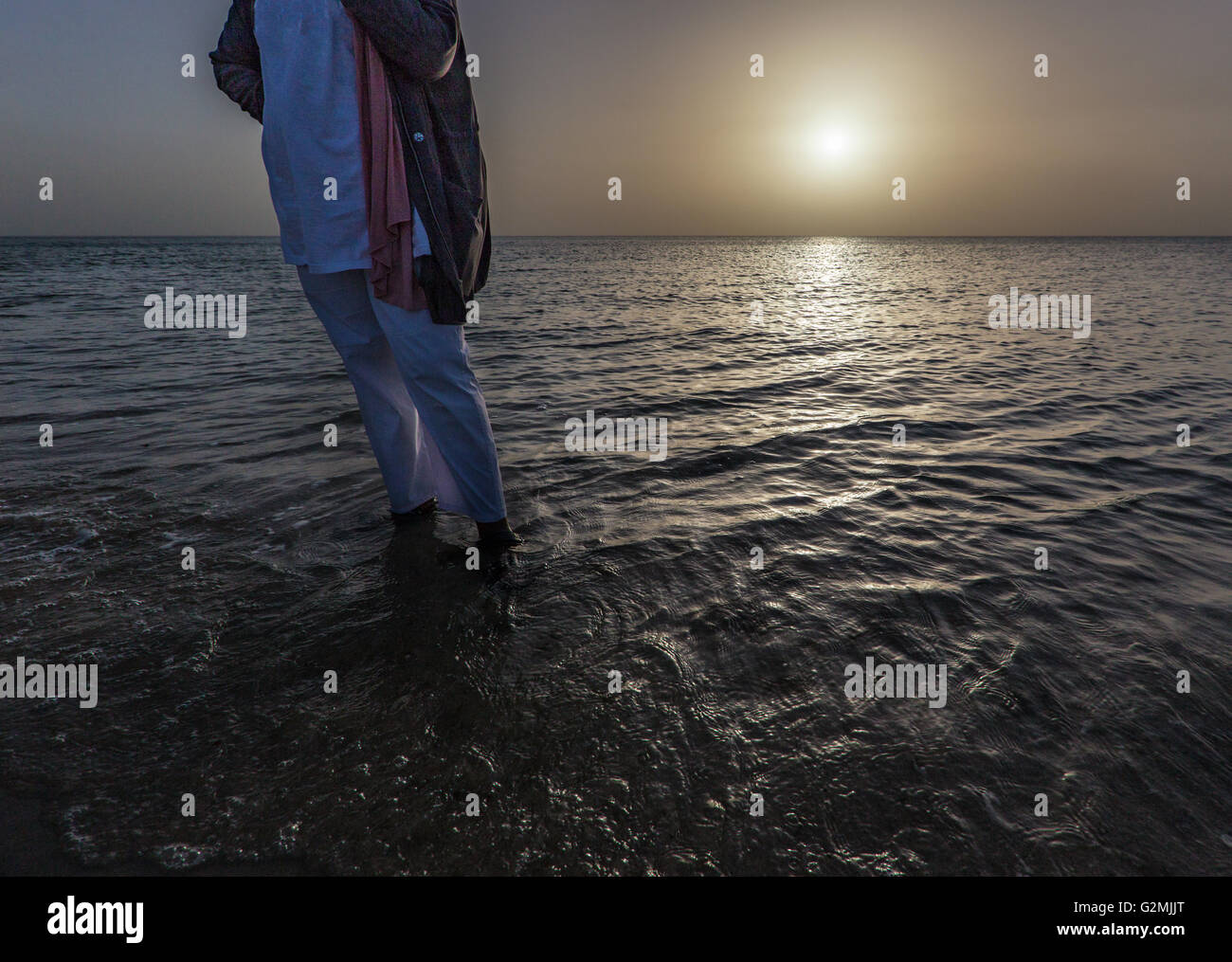 Seule femme debout dans la mer au lever du soleil au Koweït Banque D'Images