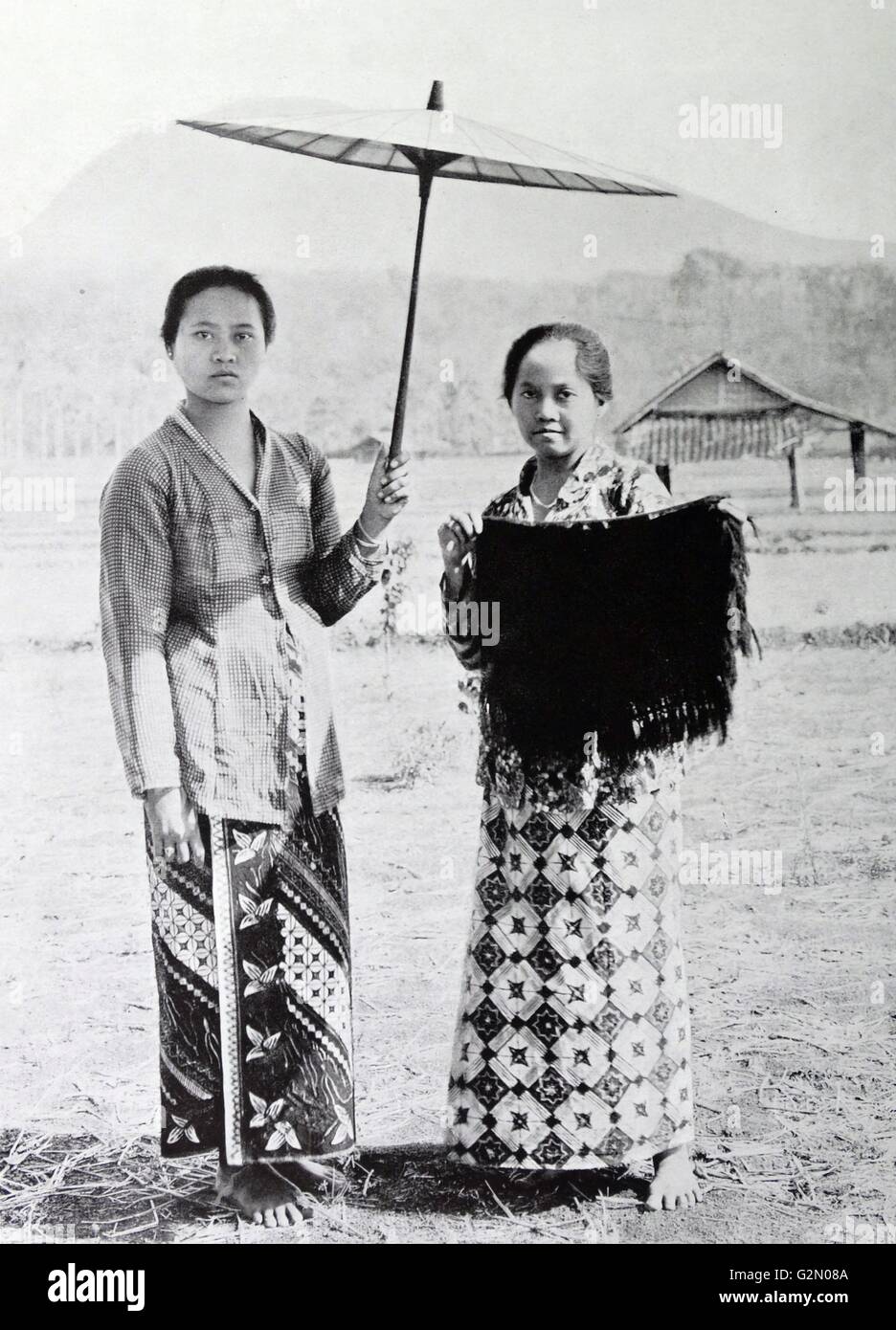 Photo montre deux figures féminines, l'une est une femme d'affaires Caine, l'autre est titulaire d'un parapluie à l'ombre du soleil. Dutch East Indies, connu sous le nom de l'Indonésie moderne. Du c1935. Banque D'Images