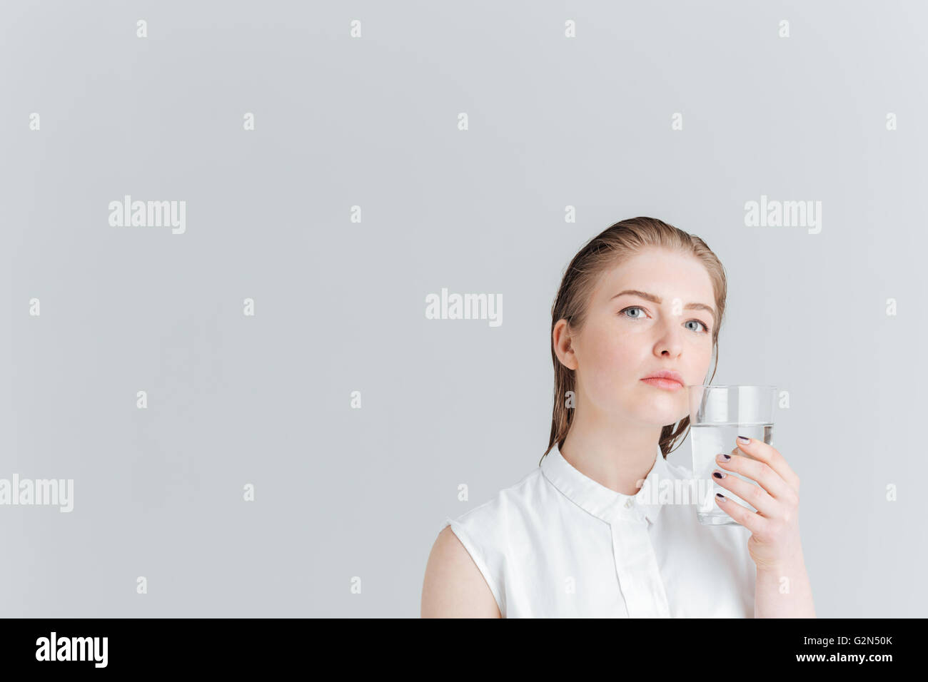 Portrait of a smiling woman holding glass of water isolé sur fond blanc Banque D'Images