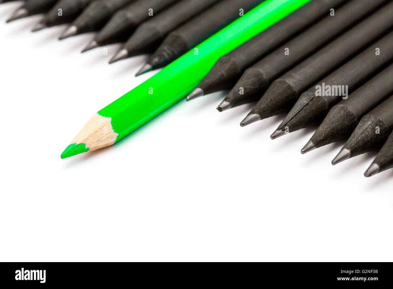 Crayon vert se démarquer de la rangée de crayons noir. Banque D'Images