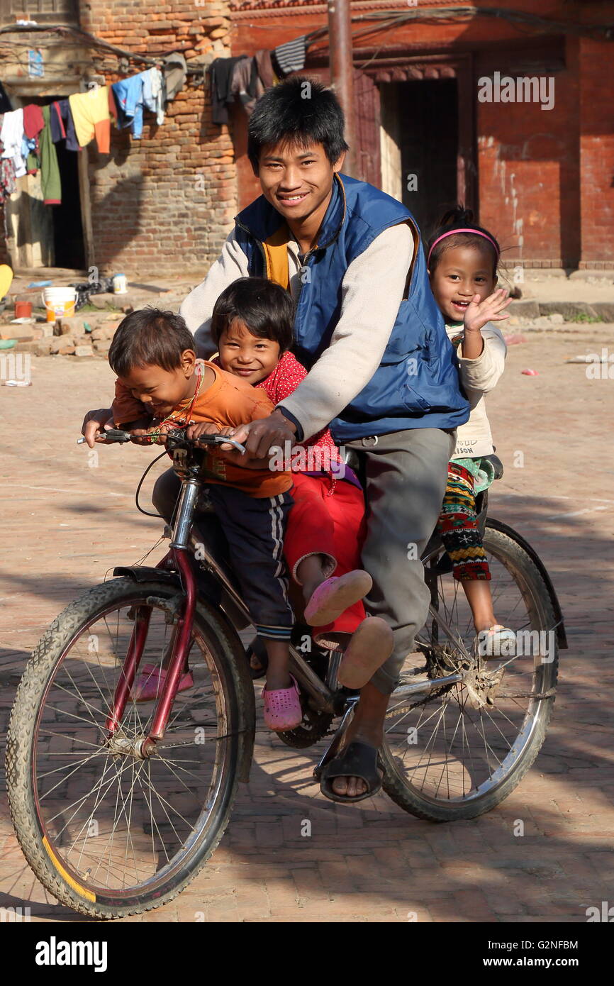 A smiling famille avec trois enfants mignons d'une bicyclette à Patan, Népal Banque D'Images