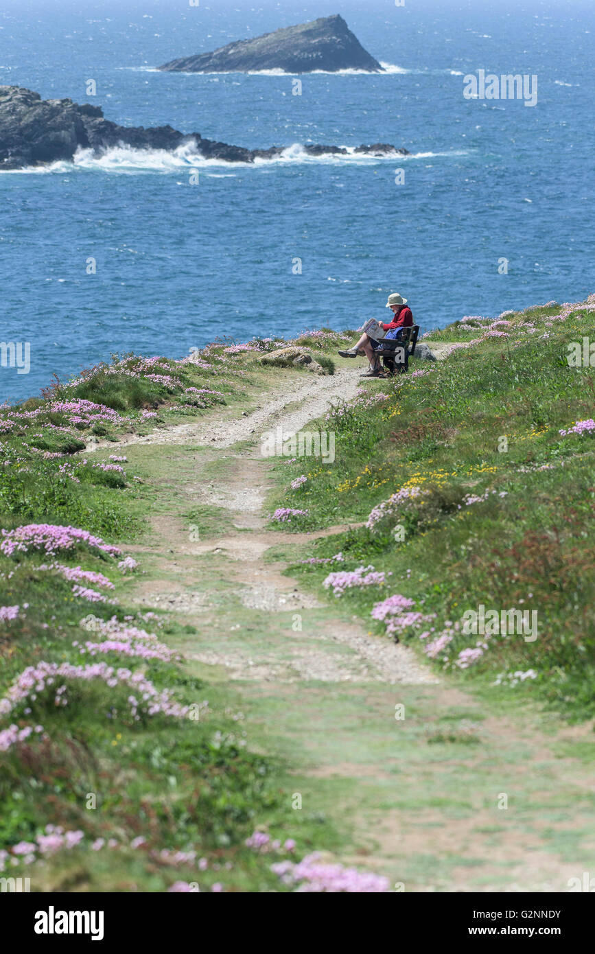 Beau temps que les marcheurs se reposer sur un banc à côté d'un sentier usé sur East Pointe Pentire à Newquay, Cornwall. Banque D'Images