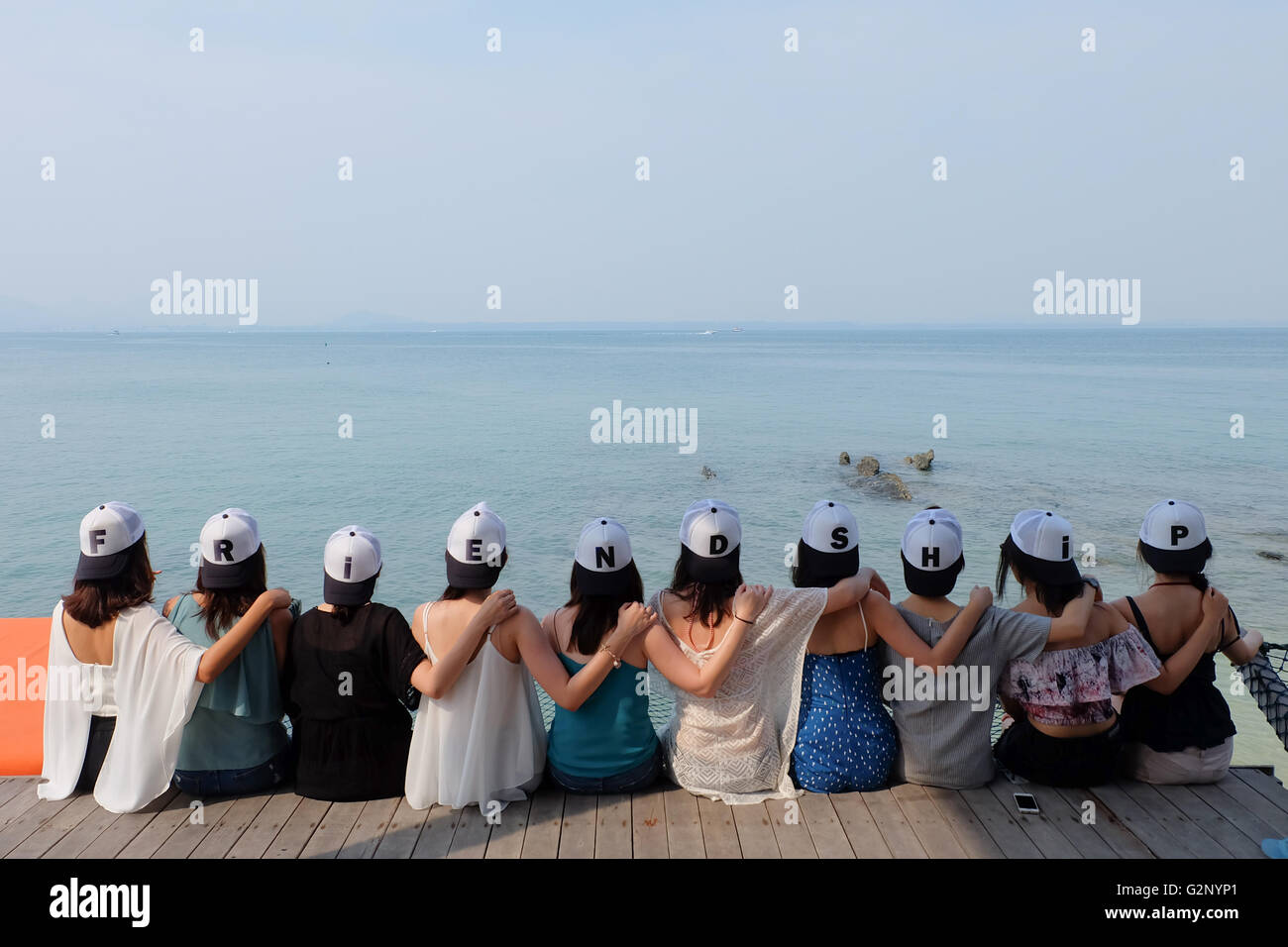 Groupe de dix femmes siéger ensemble amis hug bleu mer ciel Banque D'Images