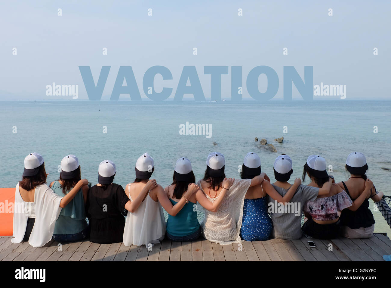 Groupe de dix femmes amis siéger hug ensemble chercher locations mer bleu ciel. Banque D'Images