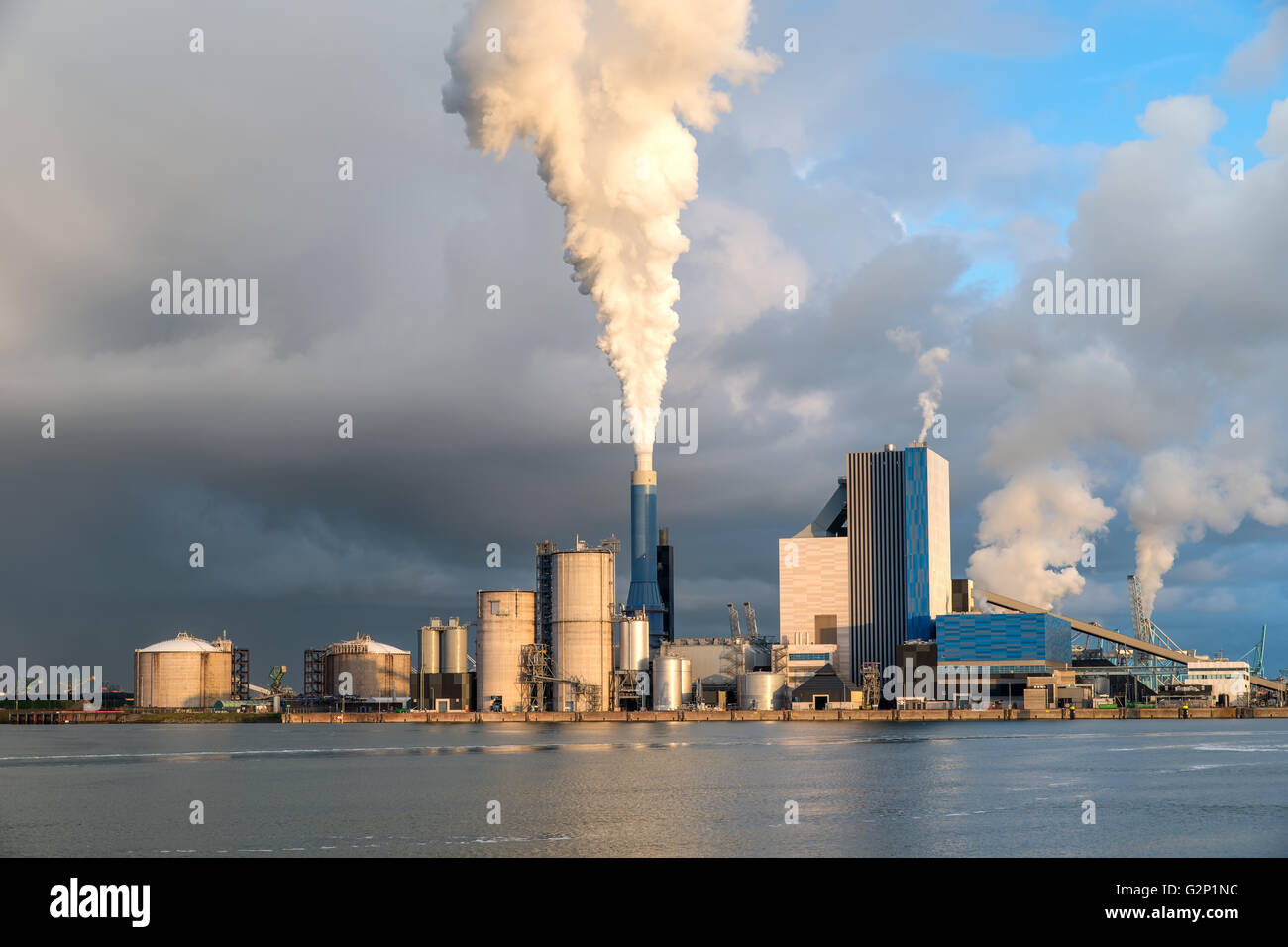 Fumeurs cheminée au coucher du soleil sur les bâtiments industriels complexes. Banque D'Images
