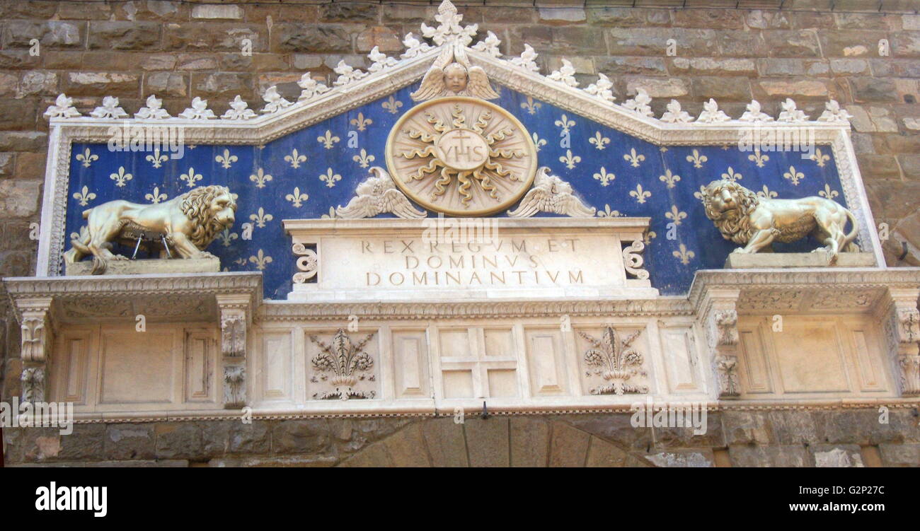 Détail de l'entrée avant le Palazzo Vecchio. Hôtel de ville de Florence, en Italie. Un immense palais-forteresse romane donnant sur la Piazza della Signoria. L'entrée présente une plante ornementale en frontispice, datant de 1528. Le monogramme du Christ se trouve au milieu, flanqué de deux lions dorés, avec le texte latin : 'Rex Regum et Dominus Dominantium". Ce qui peut être traduit comme : "par Jésus Christ, Roi des Rois et Seigneur des Seigneurs". Ce texte date de 1851. Banque D'Images