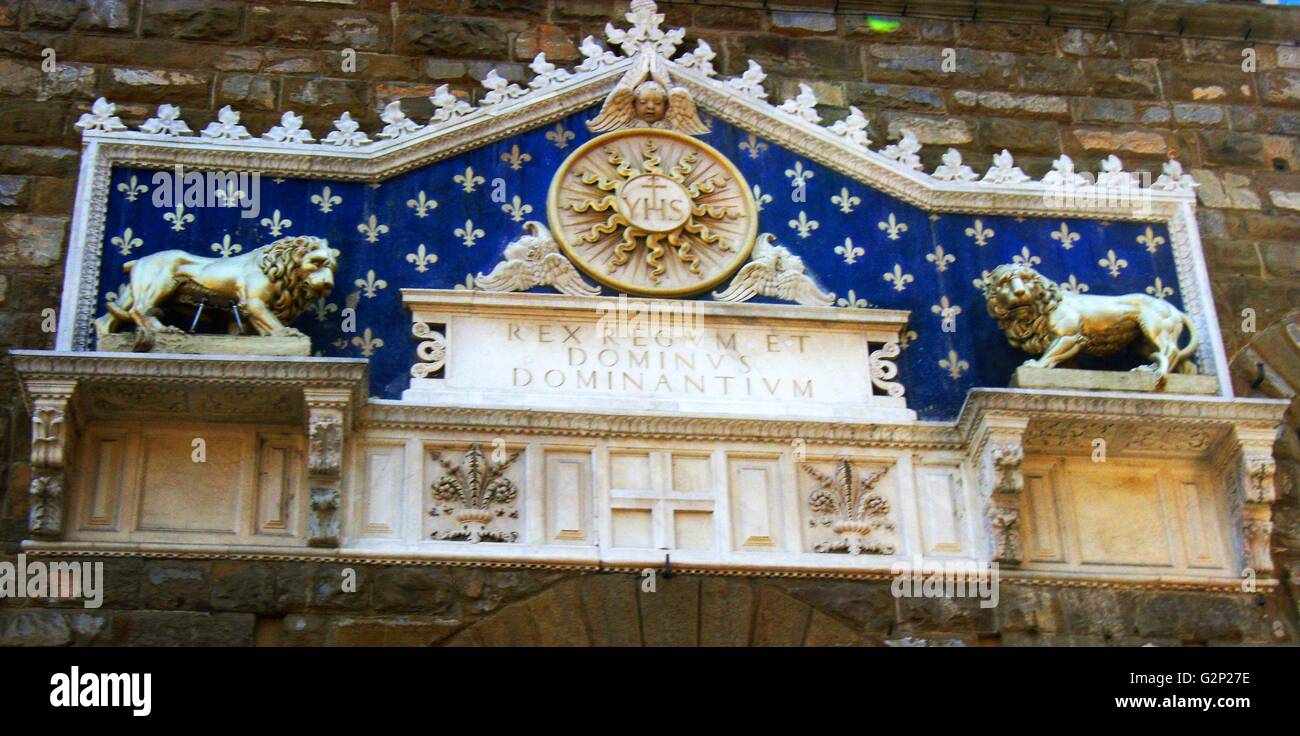 Détail de l'entrée avant le Palazzo Vecchio. Hôtel de ville de Florence, en Italie. Un immense palais-forteresse romane donnant sur la Piazza della Signoria. L'entrée présente une plante ornementale en frontispice, datant de 1528. Le monogramme du Christ se trouve au milieu, flanqué de deux lions dorés, avec le texte latin : 'Rex Regum et Dominus Dominantium". Ce qui peut être traduit comme : "par Jésus Christ, Roi des Rois et Seigneur des Seigneurs". Ce texte date de 1851. Banque D'Images