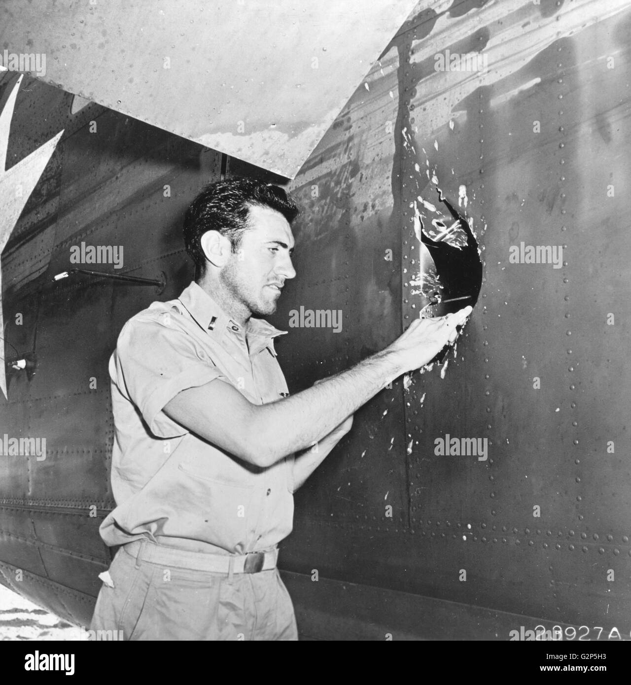 Le lieutenant Louis Zamperini (ex-miler NCAA et membre de l'équipe olympique), Bombardier, examine un 20mm trou d'obus explosifs japonais sur le côté du fuselage. Banque D'Images