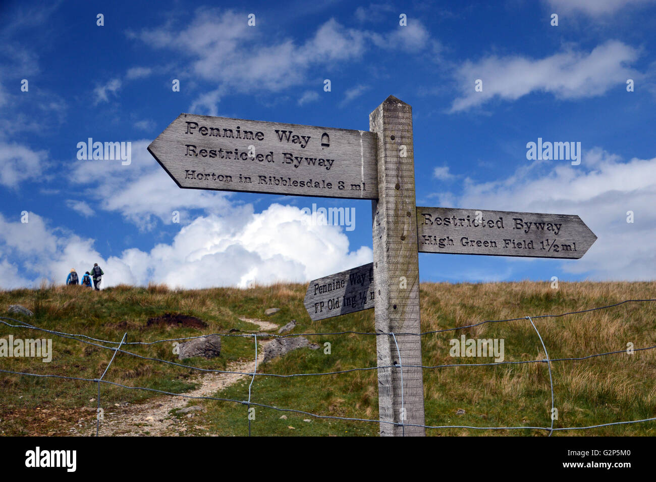 Trois marcheurs près de panneau en bois au chemin d'Junction sur la région de Pennine Way Ribblesdale dans les vallées du Yorkshire, Angleterre. Banque D'Images