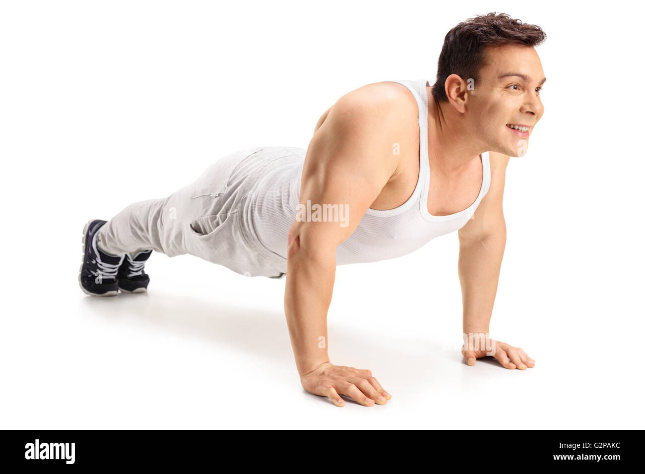 Portrait d'un jeune mec musclé faisant push-ups et souriant isolé sur fond blanc Banque D'Images