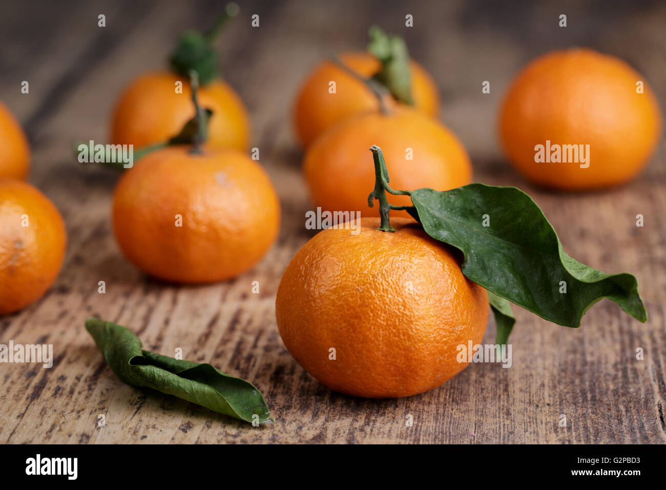 Mandarin Orange vif avec feuille verte sur planche de bois rustique Banque D'Images