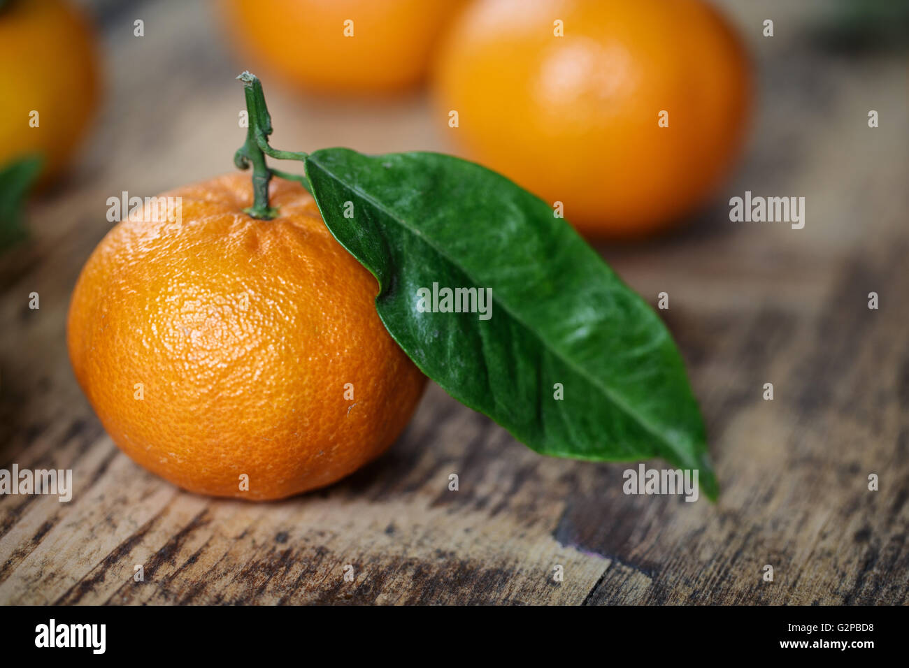 Mandarin Orange vif avec feuille verte sur planche de bois rustique Banque D'Images