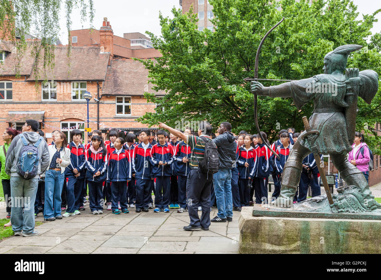 Un groupe d'élèves étrangers en voyage visiter Nottingham et debout à côté de la statue de Robin des Bois, Nottingham, England, UK Banque D'Images