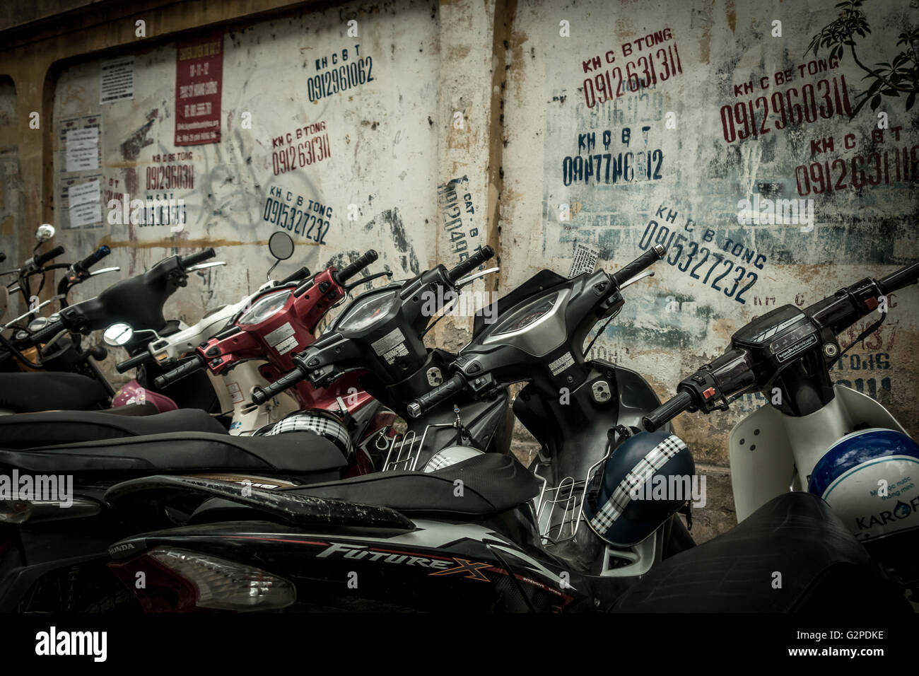 Les mobylettes alignées dans une rue latérale avec un mur de graffiti, Hanoi, Vietnam Banque D'Images