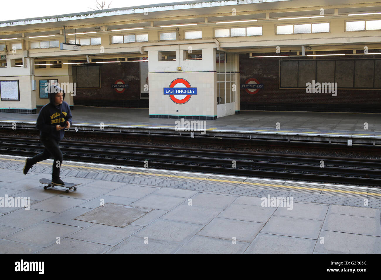 Garçon rides skateboard sur la plate-forme à l'intérieur de la station de métro East Finchley Banque D'Images