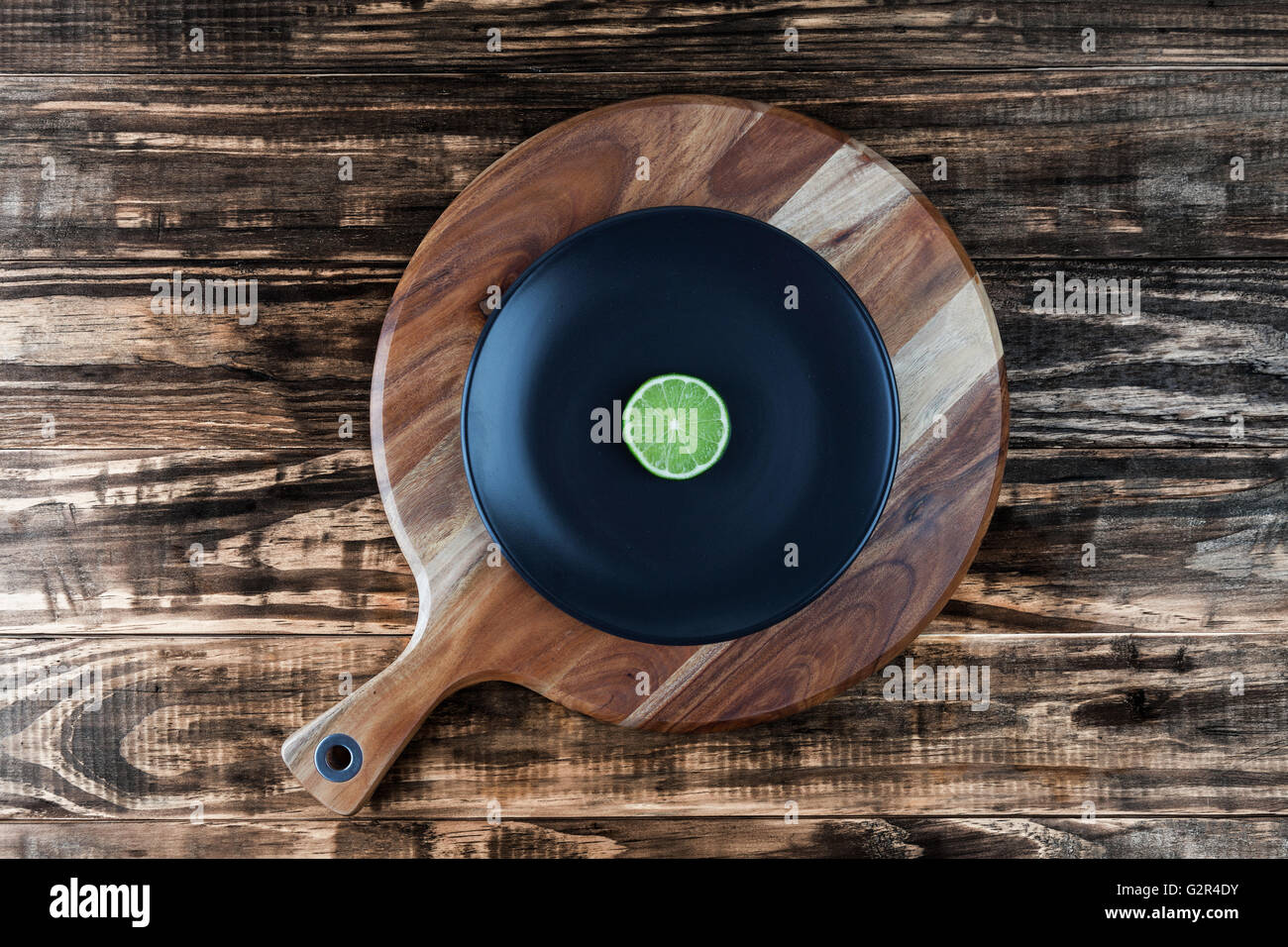 Tranche de lime sur la plaque noire et planche à découper ronde. Ressemble à l'enregistrement de musique en vinyle. Vue de dessus avec l'exemplaire de l'espace. Banque D'Images