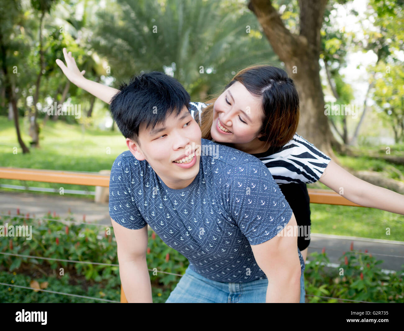 Young Asian Woman piggy back ensemble dans la nature de fond vert. Banque D'Images