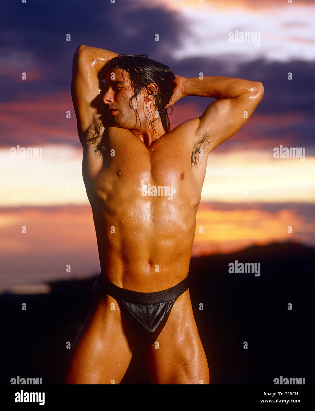 Guy s'étendant au coucher du soleil Banque D'Images