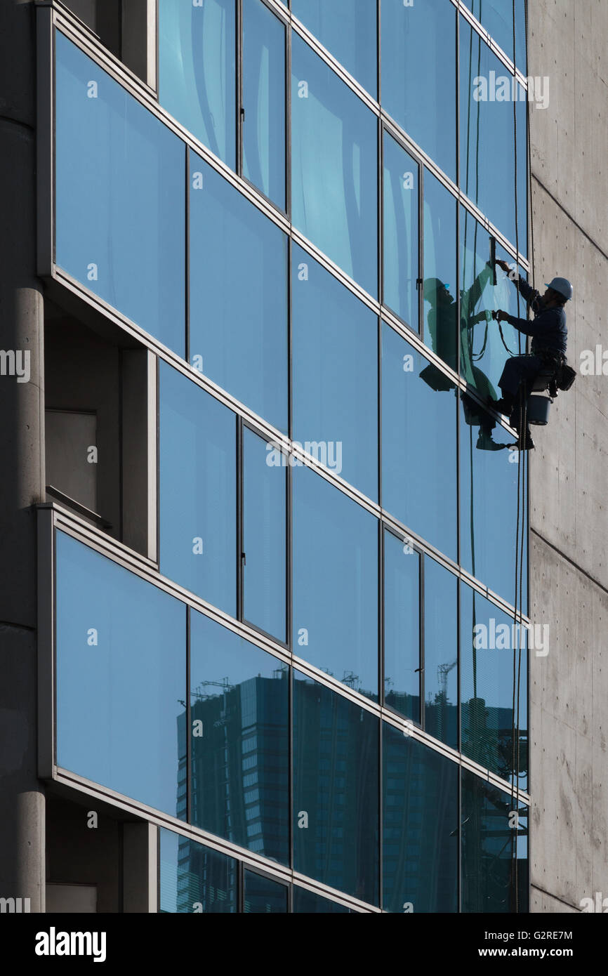 Un technicien d'accès à la corde nettoie les fenêtres d'un bâtiment près de Zoshigaya, Tokyo, Japon. Banque D'Images